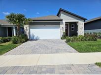 Charming single-Gathering home with a lush green yard, a paved driveway, and a two-car garage at 3776 Maxwell Park Dr, Sun City Center, FL 33573