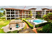 Beautiful condo exterior shows the pool and outdoor pergola seating area, with tropical plants and outdoor furniture at 6150 Gulfport S Blvd # 302, Gulfport, FL 33707