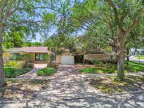 Charming single-story home featuring a brick driveway, mature trees, and manicured landscaping at 750 Alda Ne Way, St Petersburg, FL 33704