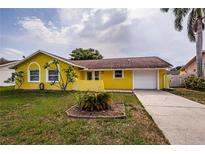 Charming yellow single-story home featuring a one-car garage and well-maintained front yard at 10051 82Nd Ln, Seminole, FL 33777