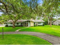 Charming single-story home with stone accents, mature trees, and a well-manicured lawn at 1675 Robin Hood Ln, Clearwater, FL 33764