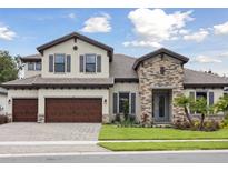Charming two-story home featuring a stone facade, three-car garage, and well-manicured lawn at 174 Hidden Estates Ct, Brandon, FL 33511