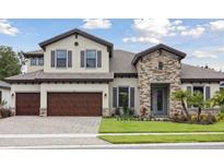 Charming two-story home featuring a three-car garage, stone accents, and a well-manicured lawn at 174 Hidden Estates Ct, Brandon, FL 33511
