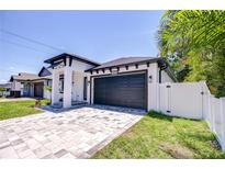 Modern home exterior with a paved driveway, black trim, and lush green lawn at 3004 W Abdella St, Tampa, FL 33607