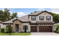 Charming two-story home with stone accents, a tile roof, a three-car garage, and manicured landscaping at 4523 Foley Grove Dr, Valrico, FL 33596