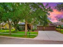 Charming home featuring a lush lawn, mature trees, and a stone-accented facade, complemented by a wide driveway at 5825 Terncrest Dr, Lithia, FL 33547