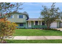 Charming two-story home with a well-manicured front yard and vibrant flowering trees at 6009 Wilshire Dr, Tampa, FL 33615