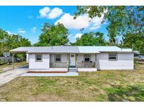 Charming single-story home features a covered porch, gray metal roof, white brick exterior, and well-maintained landscaping at 6020 N 50Th St, Tampa, FL 33610