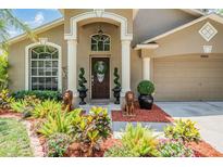 Charming front entrance with a well-manicured lawn, sculpted shrubbery, and a welcoming front door at 12813 Kings Lake Dr, Gibsonton, FL 33534