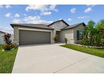Charming single-Gathering home features a two-car garage, stone accents, and a beautifully landscaped front yard at 13603 Wild Ginger St, Riverview, FL 33579