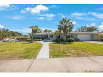 Charming single-story home with mature landscaping, palm trees and walkway leading to front door at 14204 Yacht Club Blvd, Seminole, FL 33776