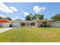 Charming single-story home featuring a well-manicured front yard, attached garage, and inviting entryway at 1445 Wilson Rd, Clearwater, FL 33755