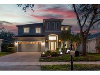 Beautiful two-story home boasting an attached two-car garage, brick driveway, and manicured landscaping at dusk at 16206 Nottingham Park Way, Tampa, FL 33647