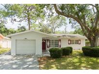 Charming single-story home featuring a one-car garage, red shutters, and lush green landscaping at 2222 Euclid N Cir, Clearwater, FL 33764
