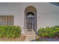 Arched entryway with security door and lush landscaping at 2749 Countryside Blvd # 4, Clearwater, FL 33761