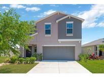 Charming two-story home with gray stucco, a well-maintained lawn, and a spacious two car garage at 10142 Golden Wonder Ln, Riverview, FL 33578