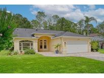 Charming home with manicured lawn, arched entry, paver driveway, and attached two-car garage at 13038 Royal George Ave, Odessa, FL 33556