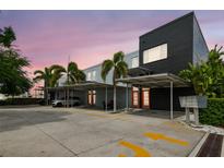 Modern condo featuring covered parking, bright orange doors, and lush tropical landscaping at dusk at 2505 W Azeele St, Tampa, FL 33609