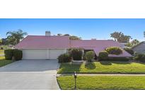 Charming single-story home featuring a unique pink roof and well-maintained landscaping at 2886 Green Meadow Ct, Clearwater, FL 33761