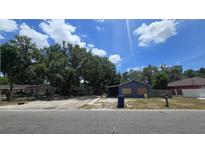 Modest single-Gathering home featuring wood siding and a spacious front yard under a bright blue sky at 4207 Henry Ave, Tampa, FL 33610
