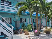 Charming teal apartment building with palm trees, green chairs, and a community grill area at 504 67Th Ave # 4, St Pete Beach, FL 33706