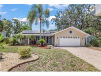 Charming single-story home featuring a well-manicured front yard, a two-car garage, and solar panels at 5761 Colonial Dr, New Port Richey, FL 34653