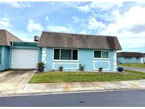 Charming single-story home features a light blue exterior, well-maintained landscaping, and an attached garage at 6880 Versailles N, Pinellas Park, FL 33781