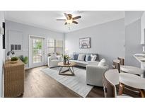 Bright living room featuring a ceiling fan, hardwood floors, stylish furniture, and a sliding glass door to the balcony at 800 S Dakota Ave # 241, Tampa, FL 33606
