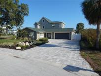 Charming two-story home with a paved driveway, mature landscaping, and a two-car garage at 8025 Island Dr, Port Richey, FL 34668
