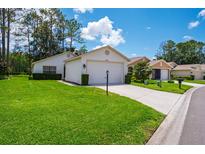 Charming single-story home featuring a well-manicured lawn and an attached two-car garage at 9500 Green Needle Dr, New Port Richey, FL 34655