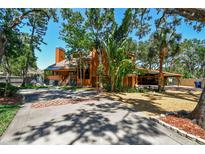 Two story home with a beautiful front yard, mature trees, and a covered carport at 11209 Spring St, Largo, FL 33774
