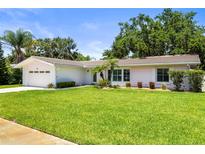 Charming single-story home featuring a lush green lawn, mature trees, and attached garage at 1140 Mcfarland St, Dunedin, FL 34698