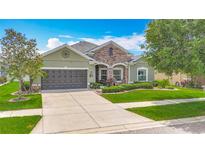 Charming one-story home featuring a stone facade, manicured lawn, and a two-car garage at 13608 Artesa Bell Dr, Riverview, FL 33579