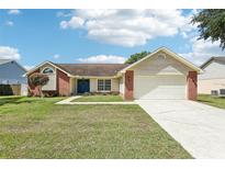 Charming single-story home with brick accents, a blue front door, and a well-maintained lawn under a bright, partly cloudy sky at 1421 Buckner Rd, Valrico, FL 33596