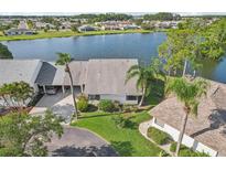 Waterfront home featuring mature landscaping, lush lawn, and views of the lake at 1613 Comfy Ct, Sun City Center, FL 33573
