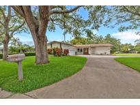 Charming single-story home featuring lush landscaping, a long driveway, and mature trees providing ample shade at 1666 Souvenir Dr, Clearwater, FL 33755