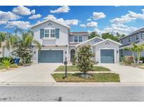 Charming two-story home with a well-maintained lawn, two-car garage, and beautiful landscaping under a partly cloudy sky at 1696 Hidden Springs Dr, Trinity, FL 34655