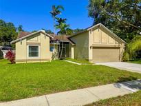Charming single-story home with manicured lawn, complemented by palm trees and well-maintained landscaping at 1955 Cobblestone Way, Clearwater, FL 33760