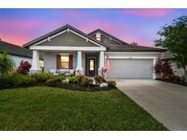 Charming single-Gathering home boasting a well-manicured lawn, vibrant flowers, and neutral gray tones at 19836 Hidden Glen Dr, Land O Lakes, FL 34638