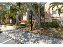 Exterior view of building featuring lush landscaping and mature trees offering shade and curb appeal at 2400 Feather Sound Dr # 1235, Clearwater, FL 33762