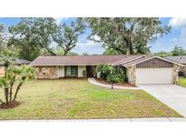 Charming single-story home with stone accents, mature trees, and a well-maintained lawn at 3604 Arlington Oaks Ct, Tampa, FL 33618