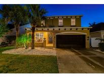 Two-story home featuring a front yard with palm trees and white rock landscaping, plus a two-car garage at 7705 S Sparkman St, Tampa, FL 33616