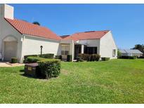 Charming home featuring a red tile roof, lush green lawn, and well-manicured landscaping at 946 Madrid Dr, Palm Harbor, FL 34684