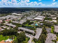 An aerial view showcases the community's landscaping, pools, and nearby shopping area with a beautiful blue sky at 14130 Rosemary Ln # 3215, Largo, FL 33774