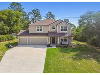Charming two-story home with a three-car garage, landscaped yard, and covered front porch at 14282 Coronado Dr, Spring Hill, FL 34609