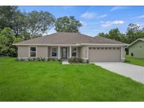Charming single-story home with lush green lawn, neutral exterior, and attached two-car garage at 27017 Mott Ave, Brooksville, FL 34602