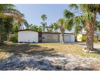 Charming single-story home with white brick, decorative privacy screen, attached garage, and tropical landscaping at 328 Tallahassee Ne Dr, St Petersburg, FL 33702