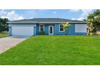 Charming single-story home showcasing a well-manicured lawn, a two car garage and a cheerful blue exterior at 461 Celeste St, Port Charlotte, FL 33954