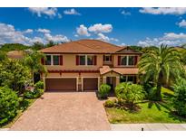 Beautiful two-story home boasting a brick driveway, tile roof, two-car garage, and mature palm trees at 4611 Grand Preserve Pl, Palm Harbor, FL 34684