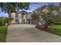 Stately two-story home with a three-car garage, lush landscaping, and an expansive driveway under a colorful sky at 4915 Augusta Ave, Oldsmar, FL 34677